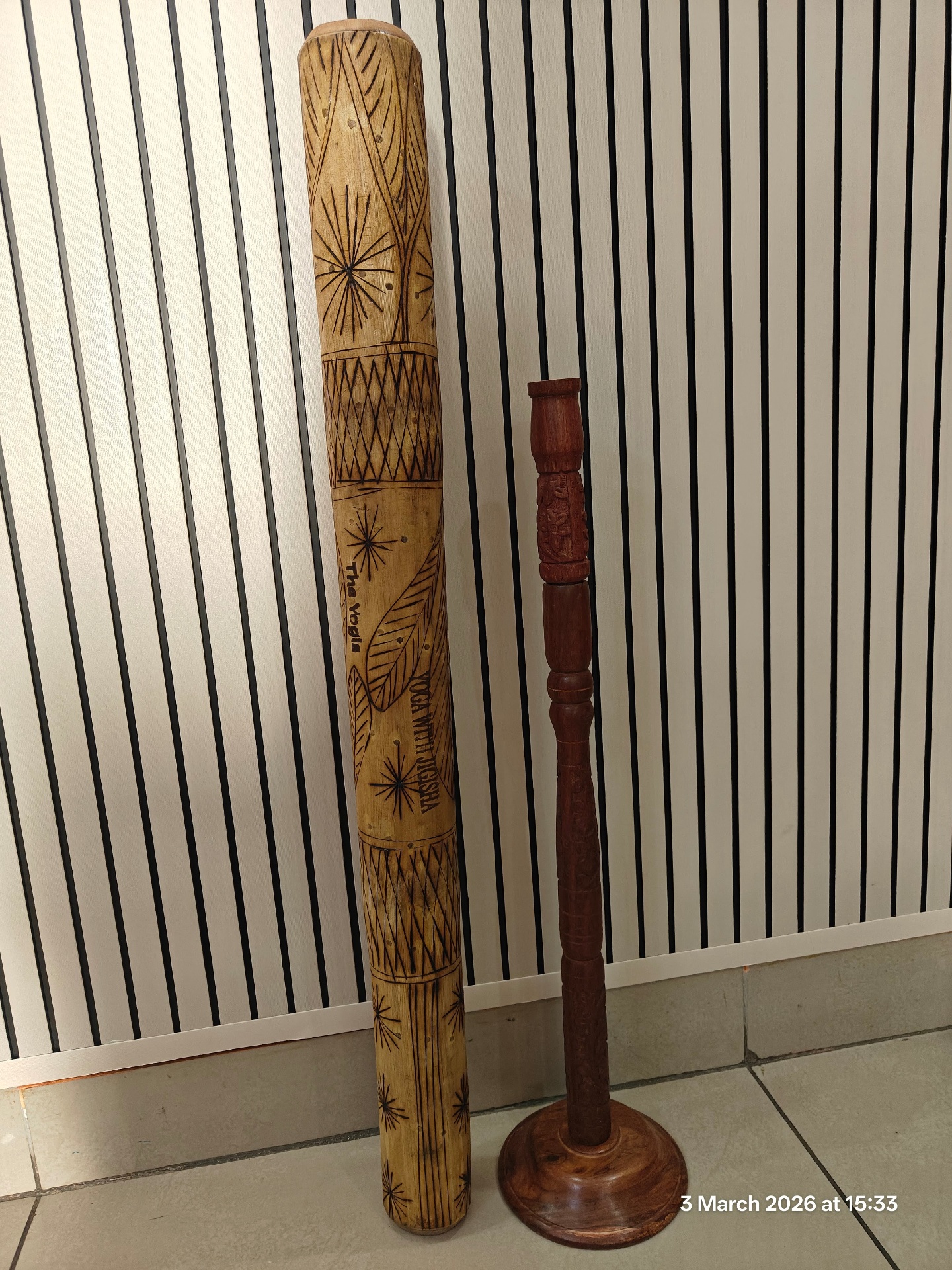 Hand-carved wooden rain stick with decorative leaf and diamond patterns engraved with 'Yoga With Jigisha The Yogis' used for sound healing meditation in Bangalore March 2026