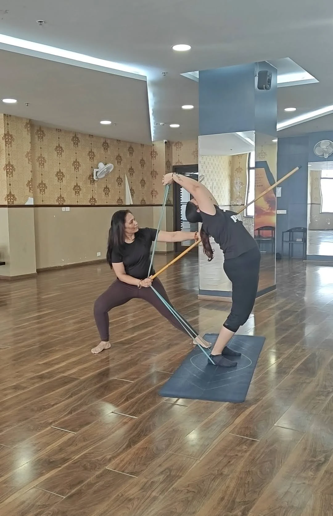 Stick Yoga Practice - Two students performing assisted backbend with yoga stick at Yoga With Jigisha studio Bangalore March 2026